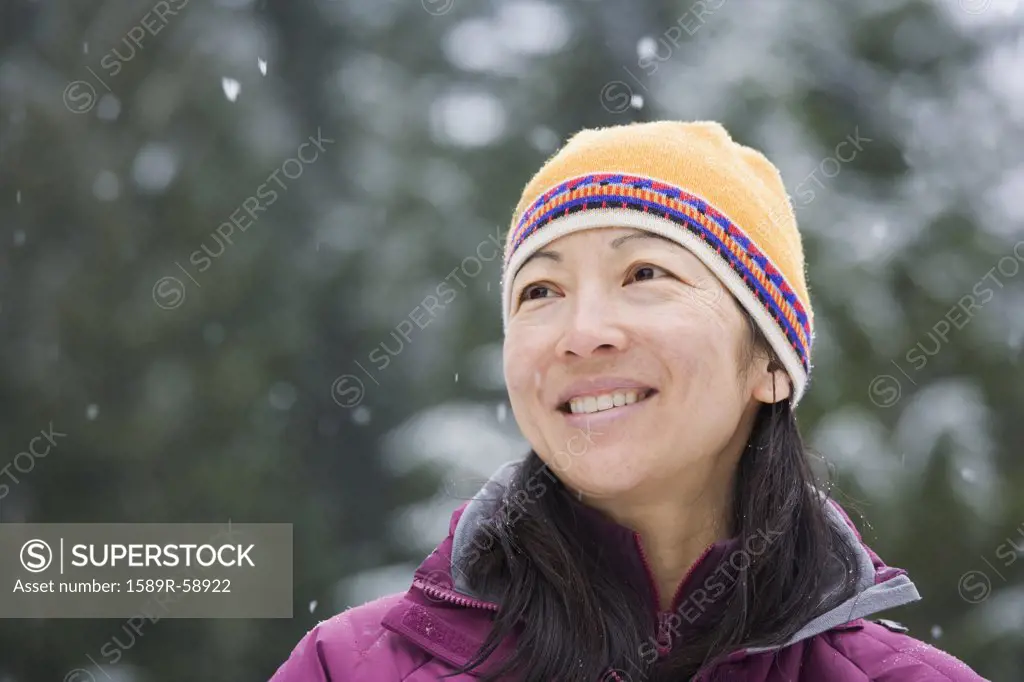 Asian woman wearing hat in snow