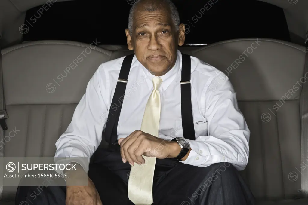 Senior African businessman in backseat of limousine