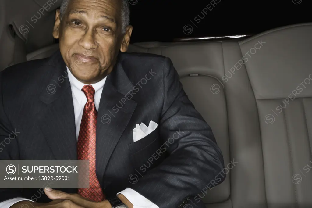 Senior African businessman in backseat of limousine