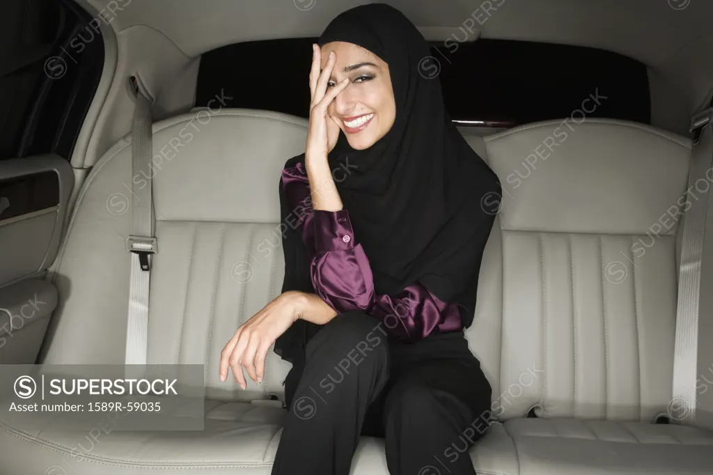 Middle Eastern businesswoman in backseat of limousine