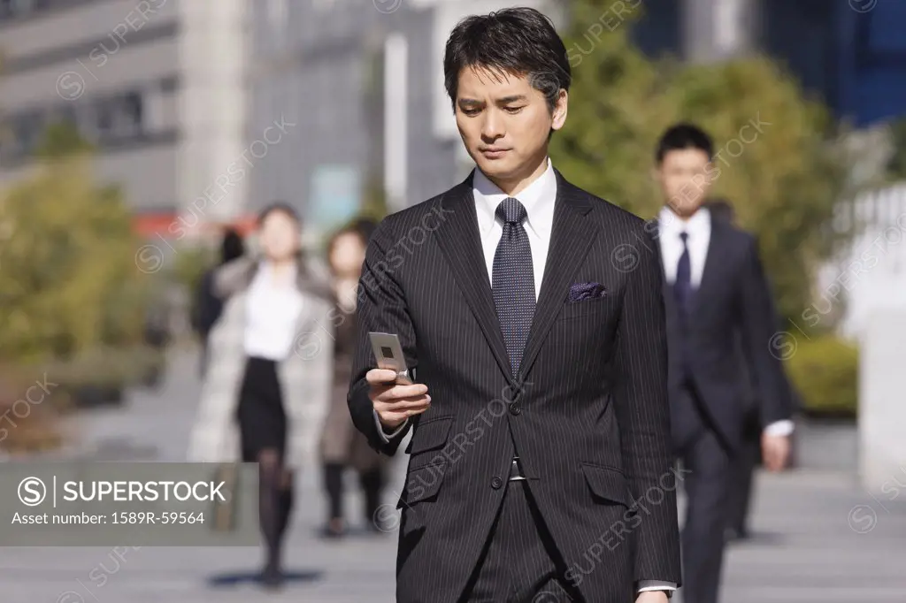 Asian businessman dialing cell phone