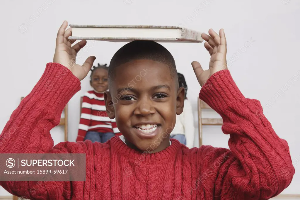 African boy holding book on head