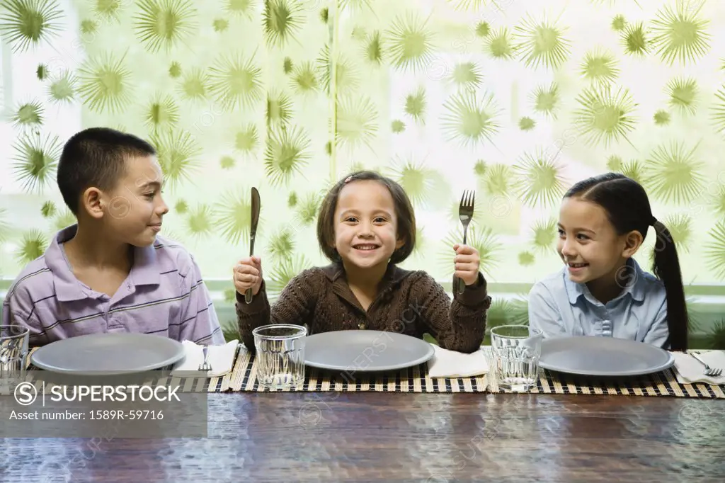 Asian siblings sitting at dinner table