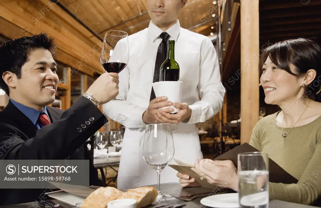 Asian man testing wine at restaurant
