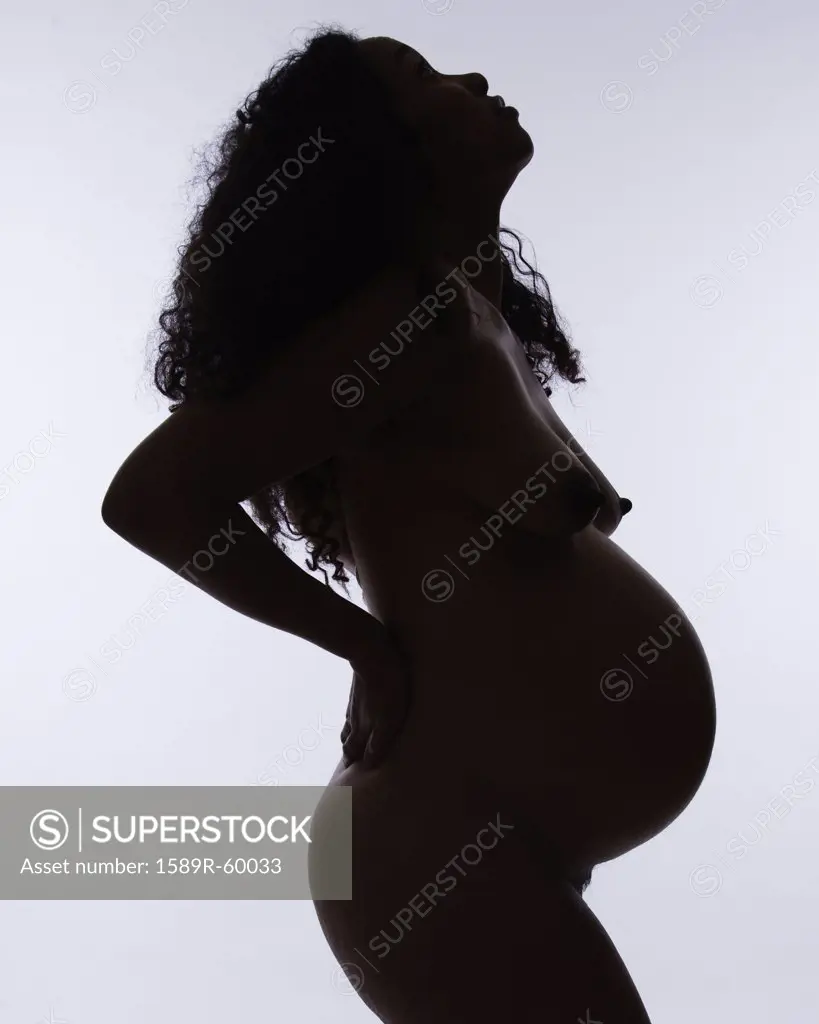 Nude pregnant Mixed Race woman with hands on back