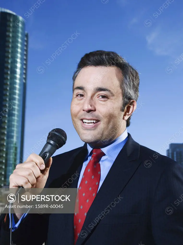 Hispanic male reporter holding microphone