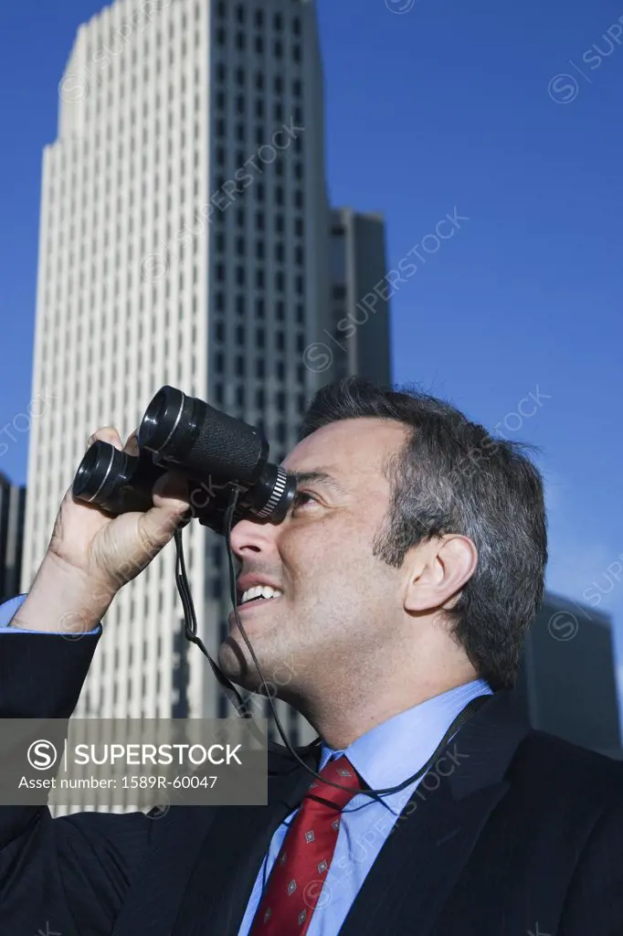 Hispanic businessman looking through binoculars