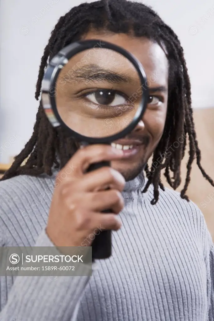 African man looking through magnifying glass