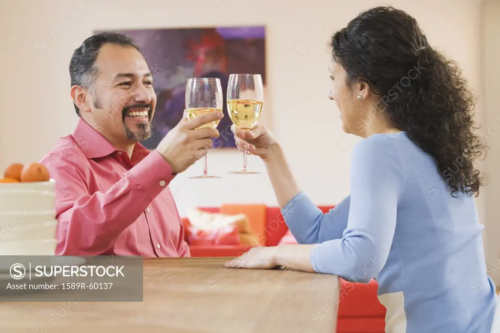 Hispanic couple toasting with wine