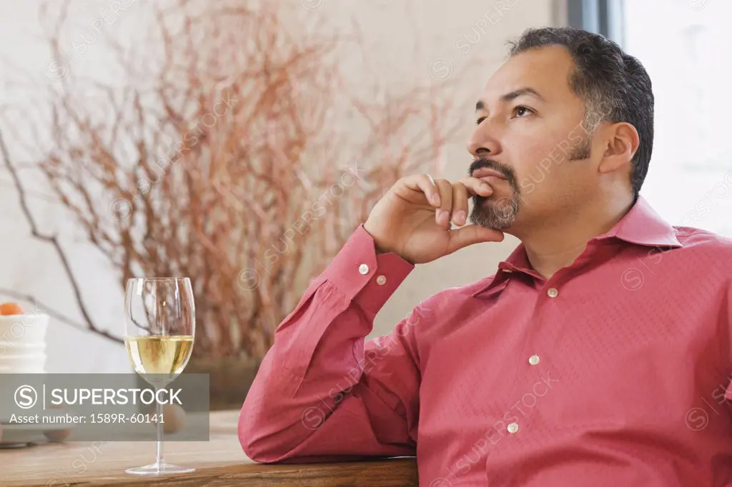 Hispanic man next to glass of wine