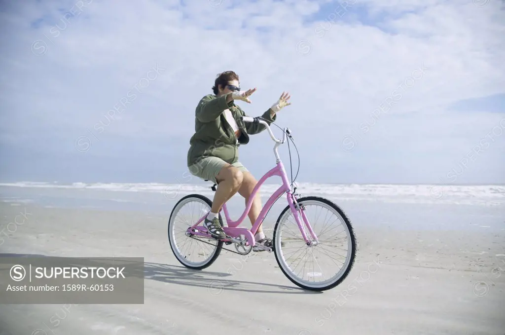Senior woman riding bicycle on beach