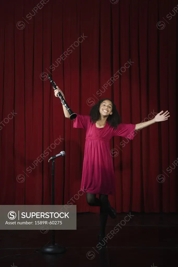 Mixed Race girl holding clarinet on stage