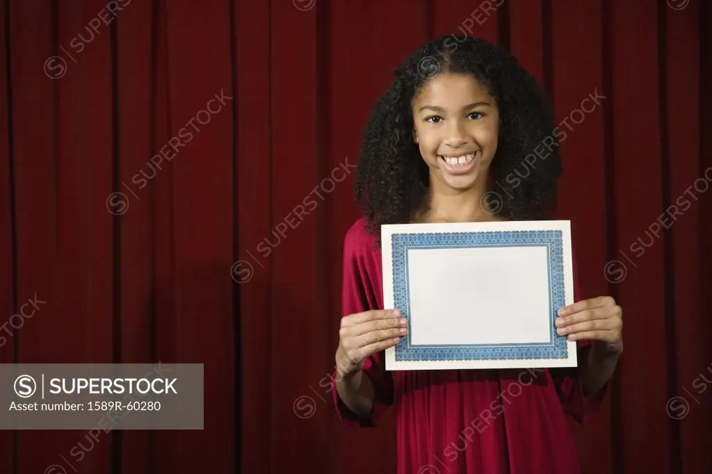 Mixed Race girl holding blank certificate on stage
