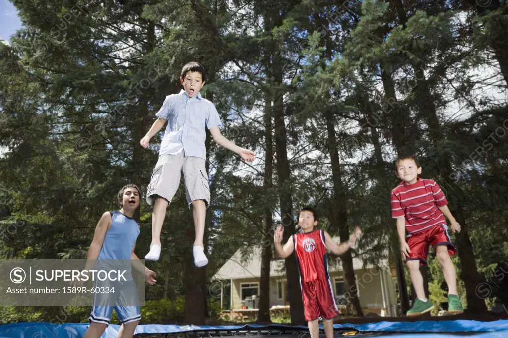 Asian brothers jumping on trampoline