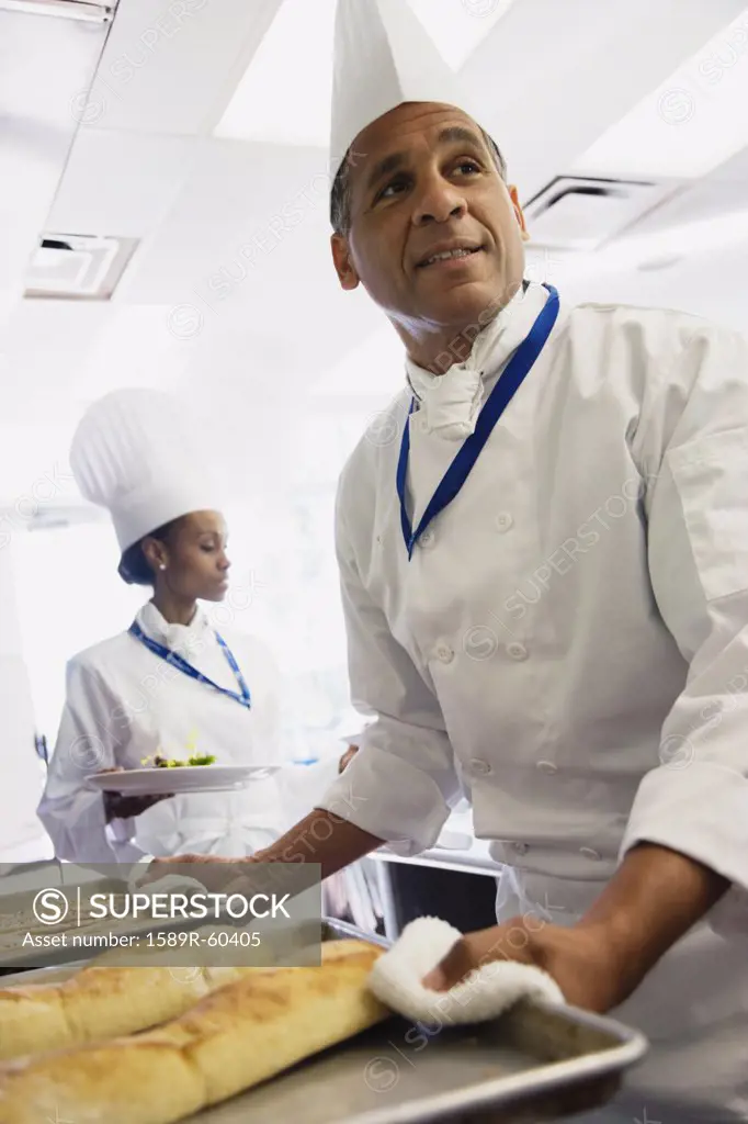 Multi-ethnic chefs carrying food in kitchen