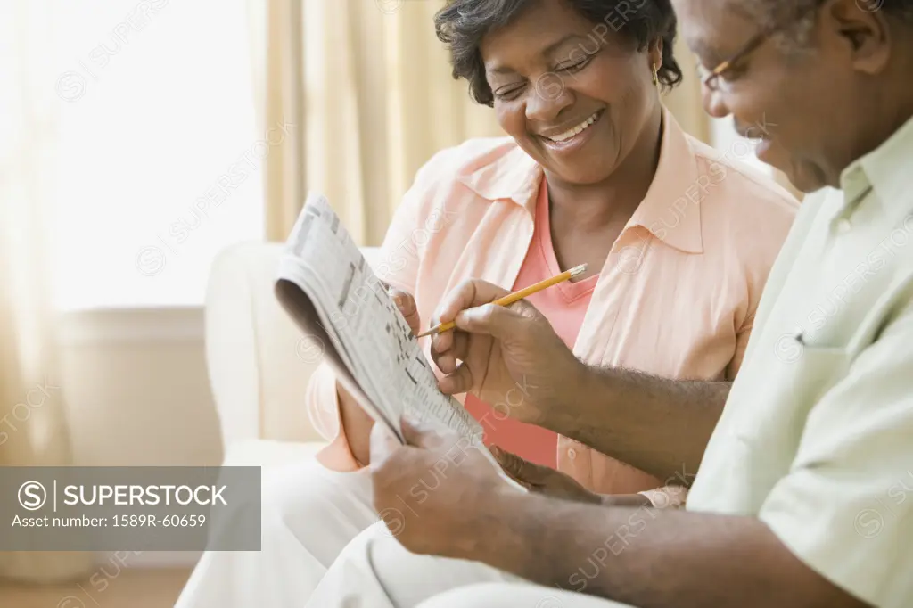 Senior African couple doing crossword puzzle
