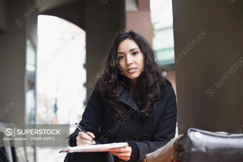 Middle Eastern woman writing in notebook
