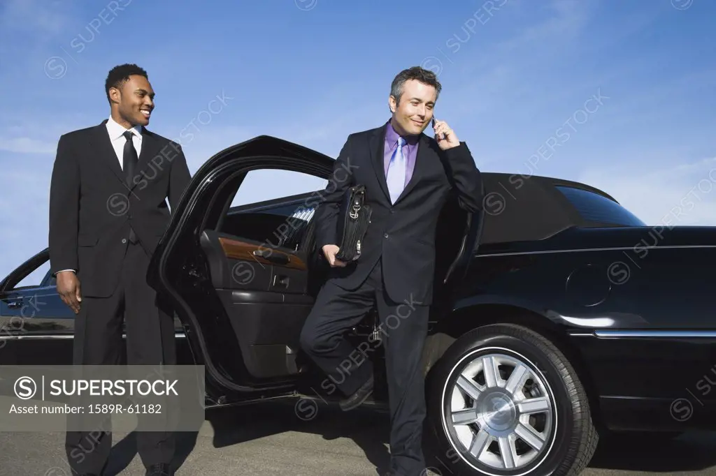Hispanic businessman getting out of limousine