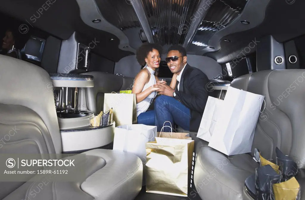 African couple with shopping bags in limousine