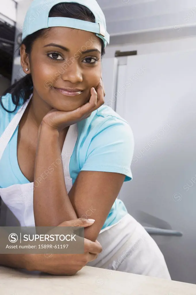 Mixed Race female kitchen worker leaning on counter