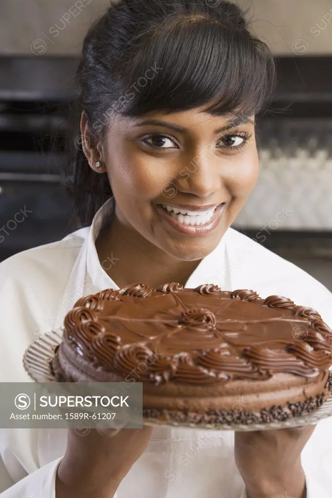 Mixed Race female pastry chef holding cake