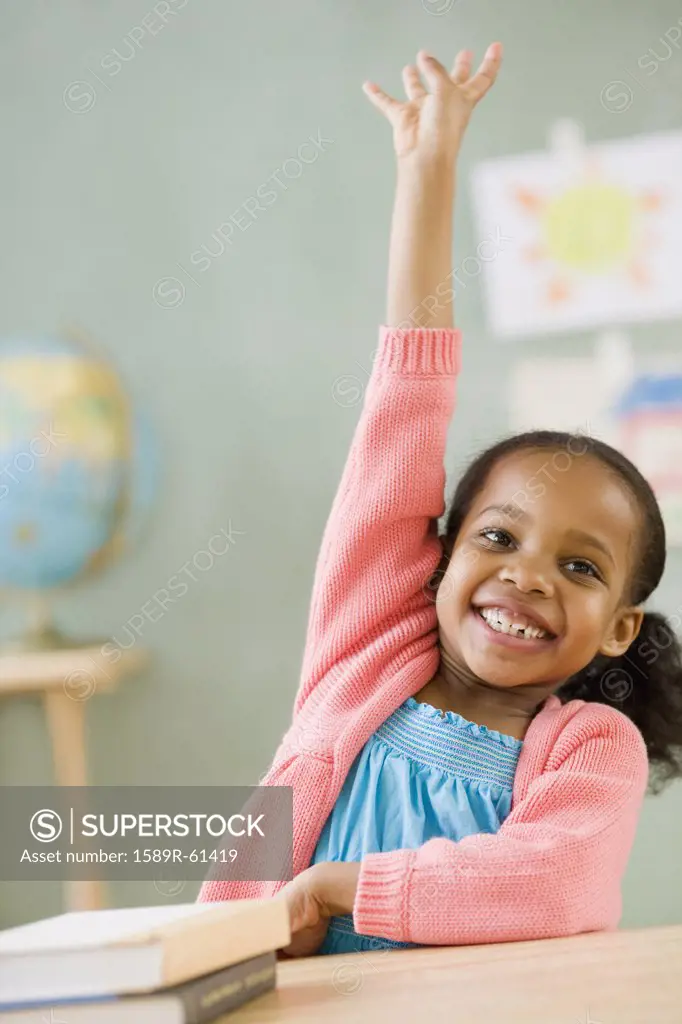 Mixed race girl raising hand to answer question