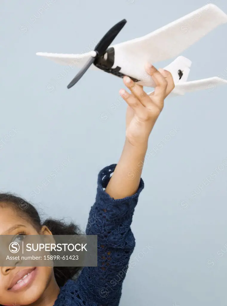 Mixed race girl playing with toy airplane