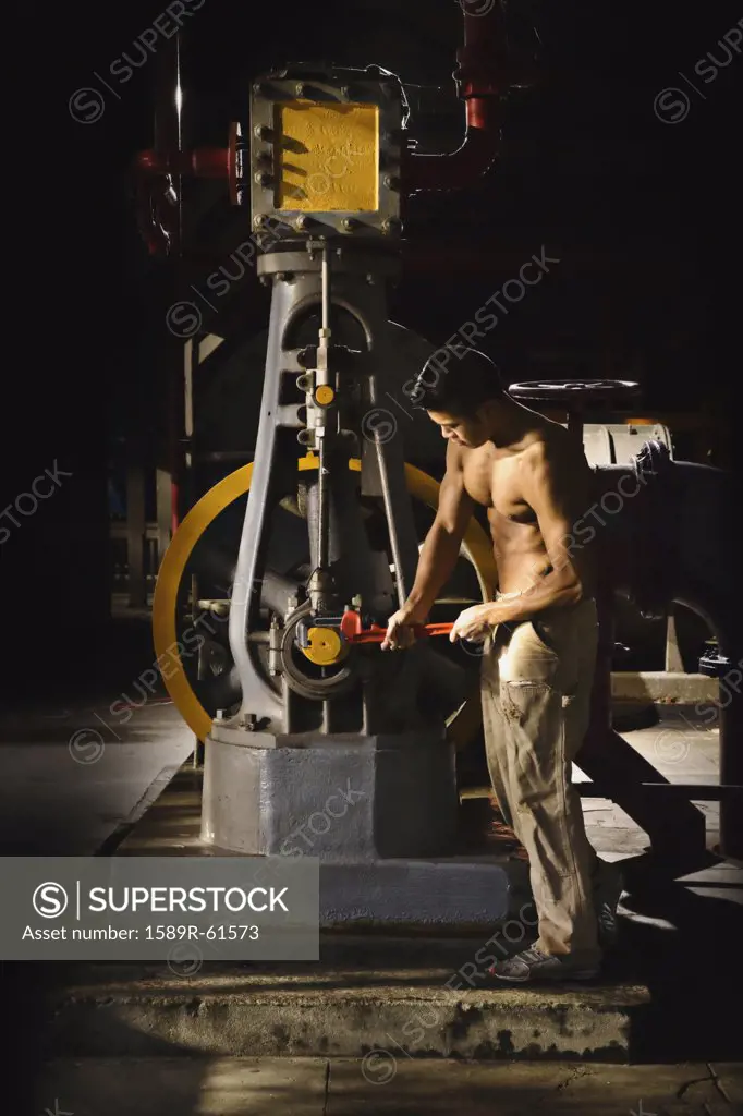 Bare chested Asian man working in factory