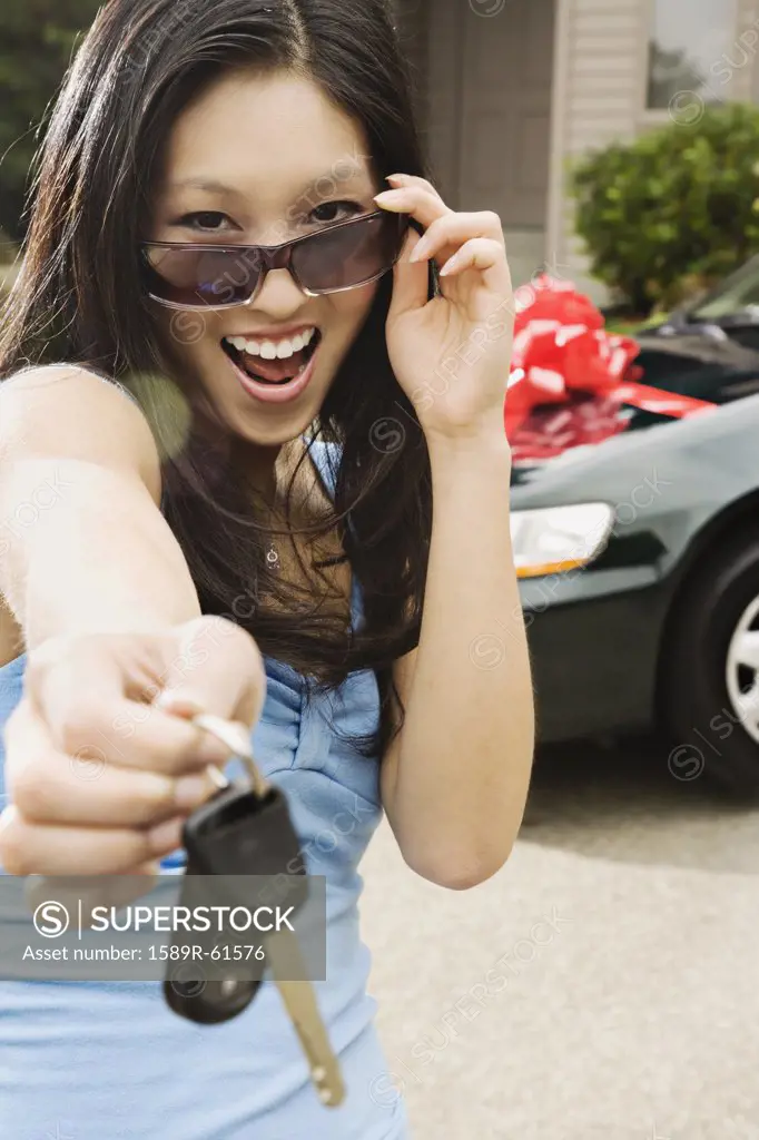 Asian teenager holding keys to new car