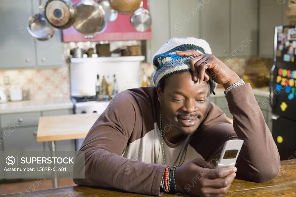 African man in kitchen checking cell phone