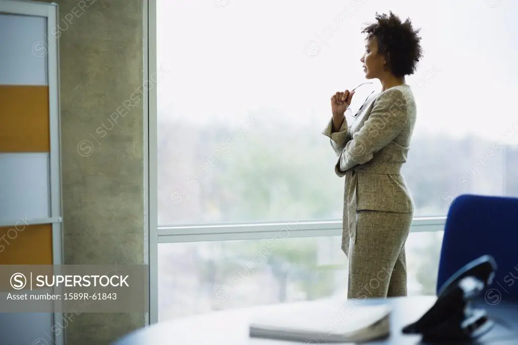 African businesswoman looking out window in office