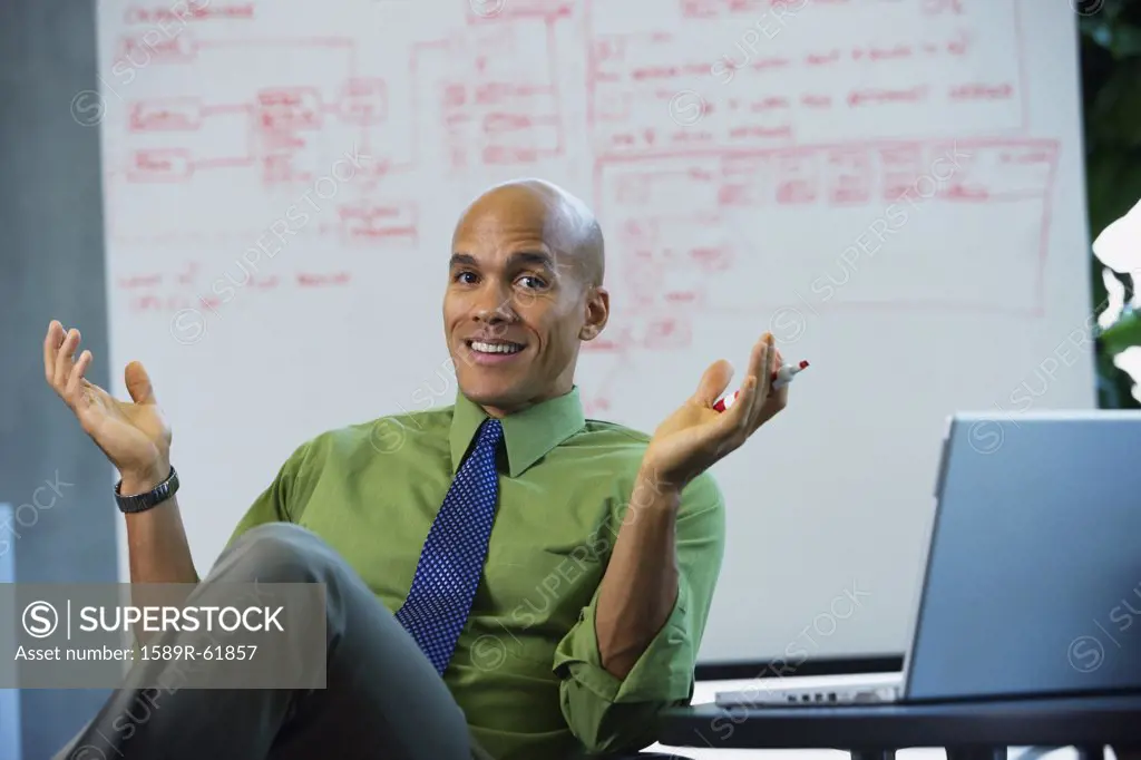 Mixed race businessman smiling and gesturing in office
