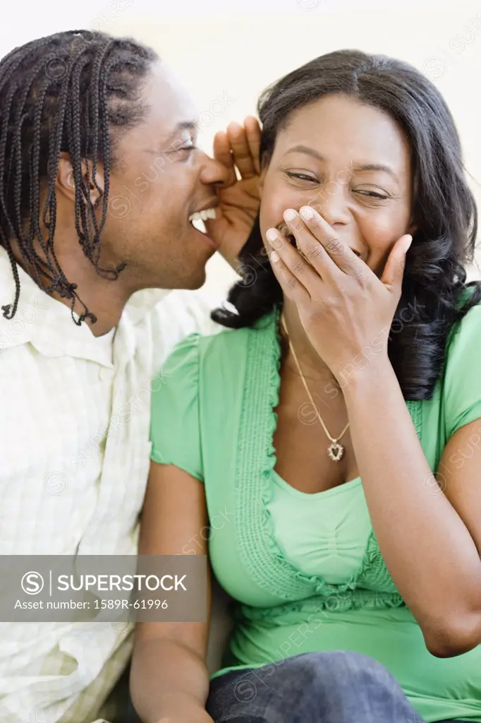 African man whispering in woman's ear