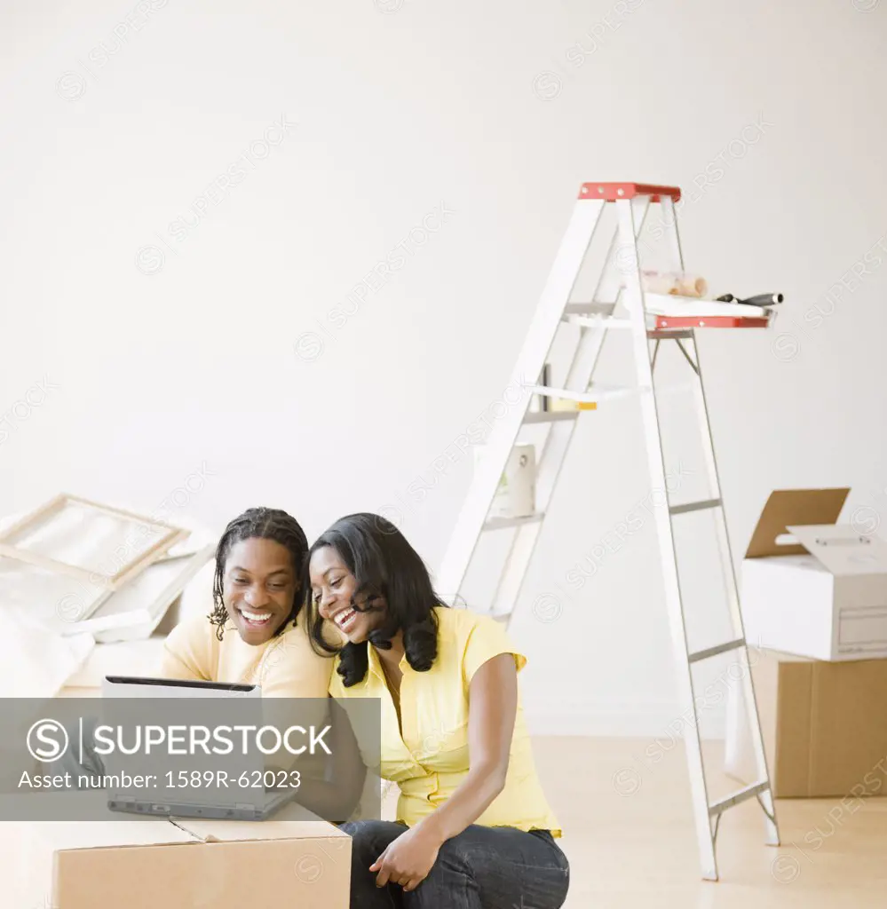 African couple on laptop with moving boxes