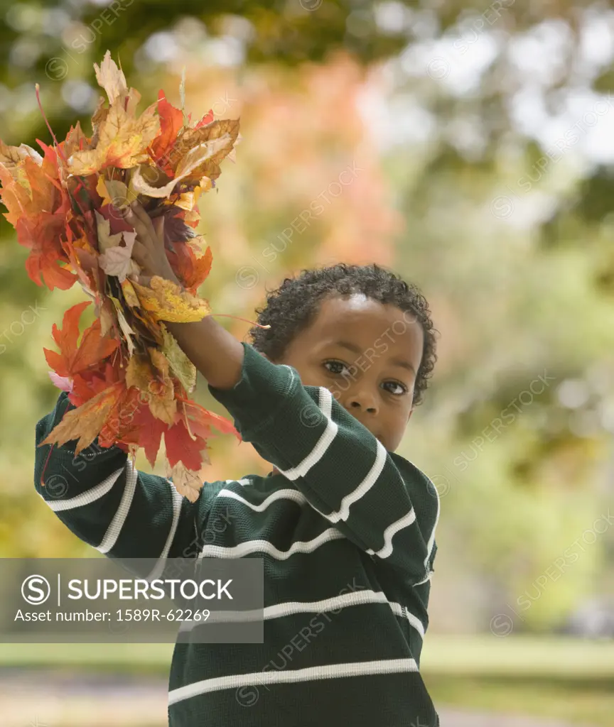 African boy holding autumn leaves