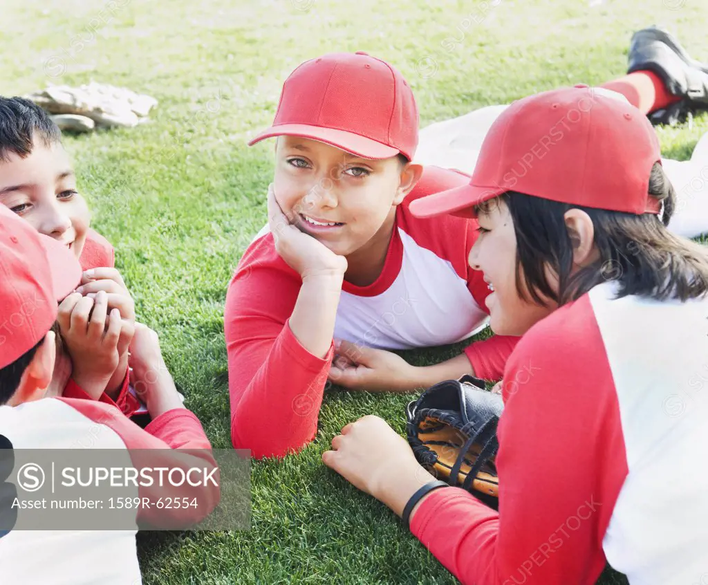 Multi-ethnic boys in baseball uniforms laying on grass
