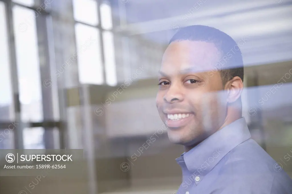 African businessman smiling through window