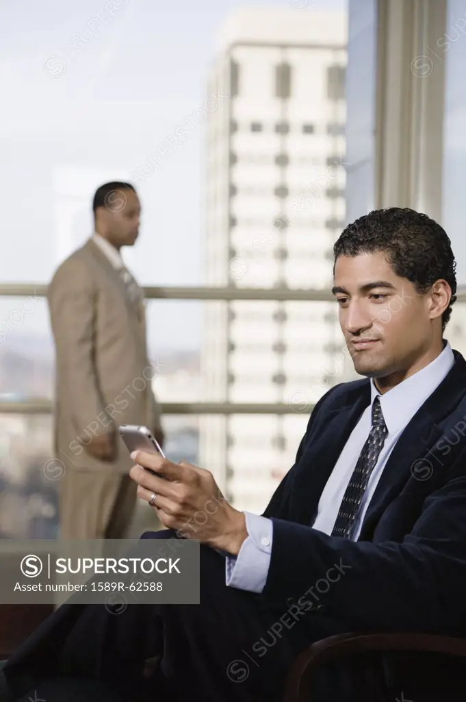 Mixed race businessman using cell phone