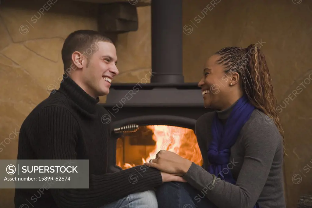 Multi-ethnic couple sitting by wood stove