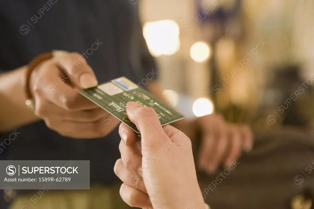 Mixed race woman handing credit card to cashier
