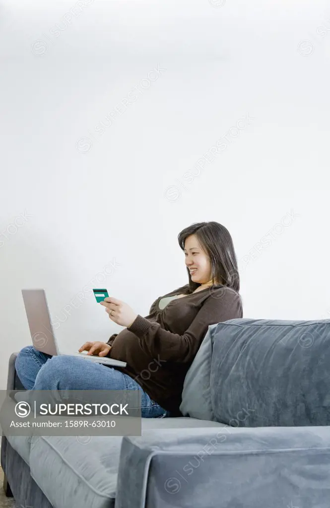 Pregnant Asian woman buying merchandise over the internet