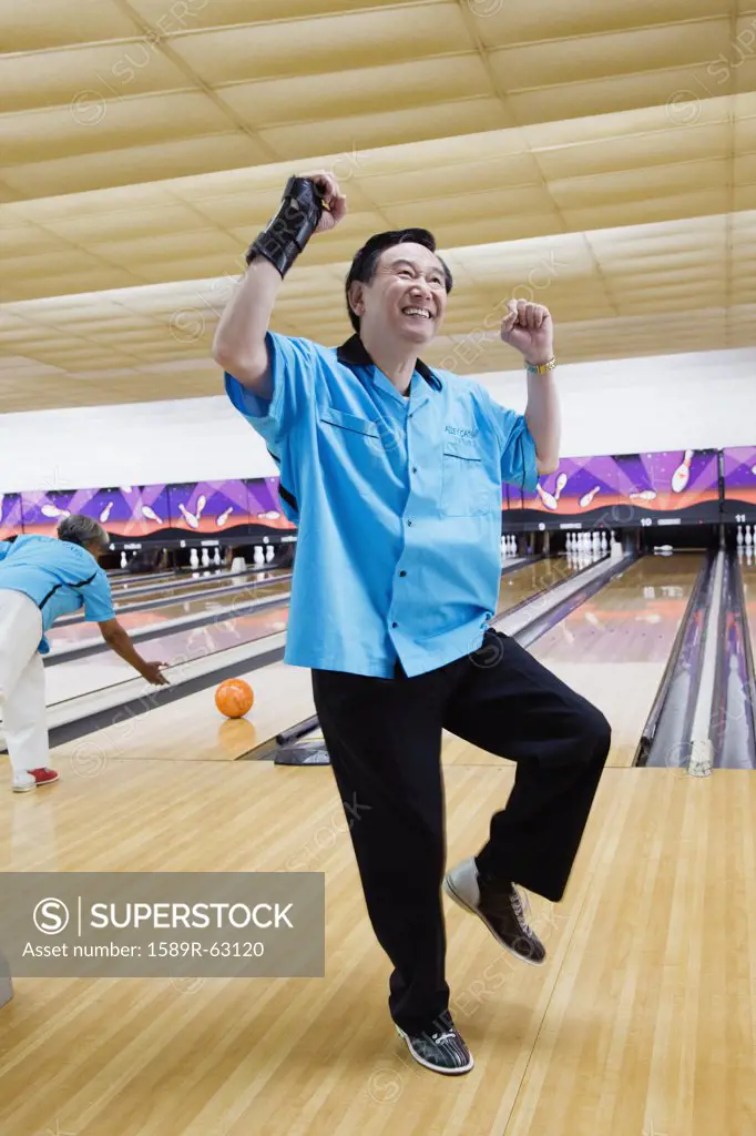 Asian man cheering in bowling alley