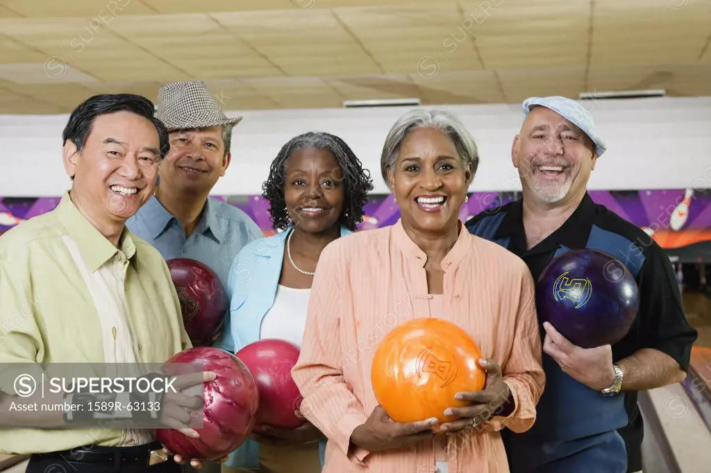 Friends holding bowling balls in bowling alley