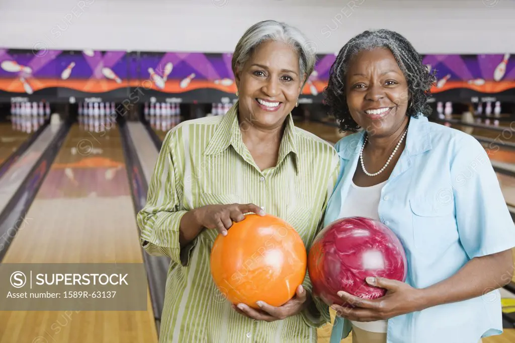 African women holding bowling balls in bowling alley