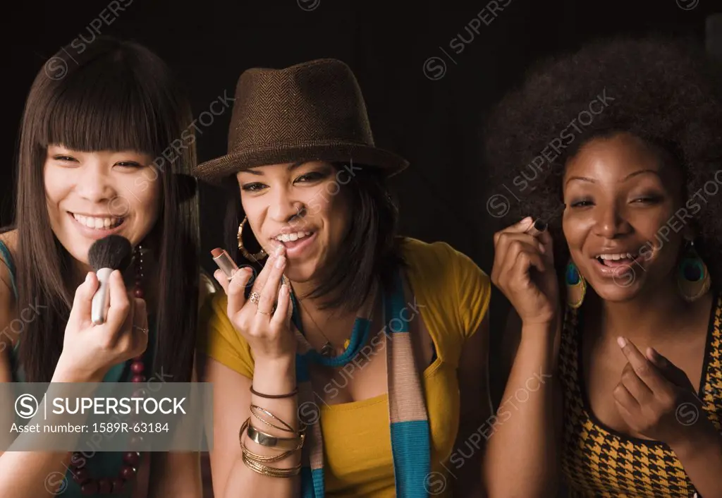 Multi-ethnic women putting on makeup