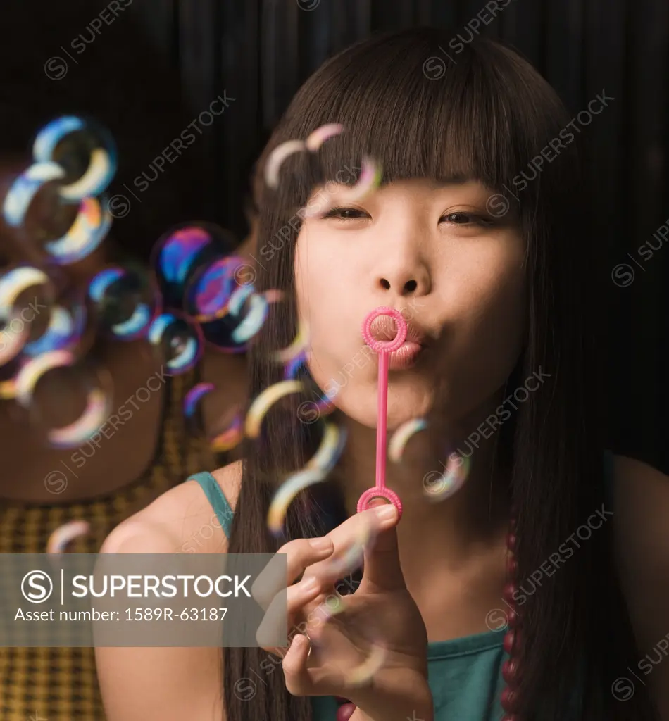 Asian woman blowing bubbles