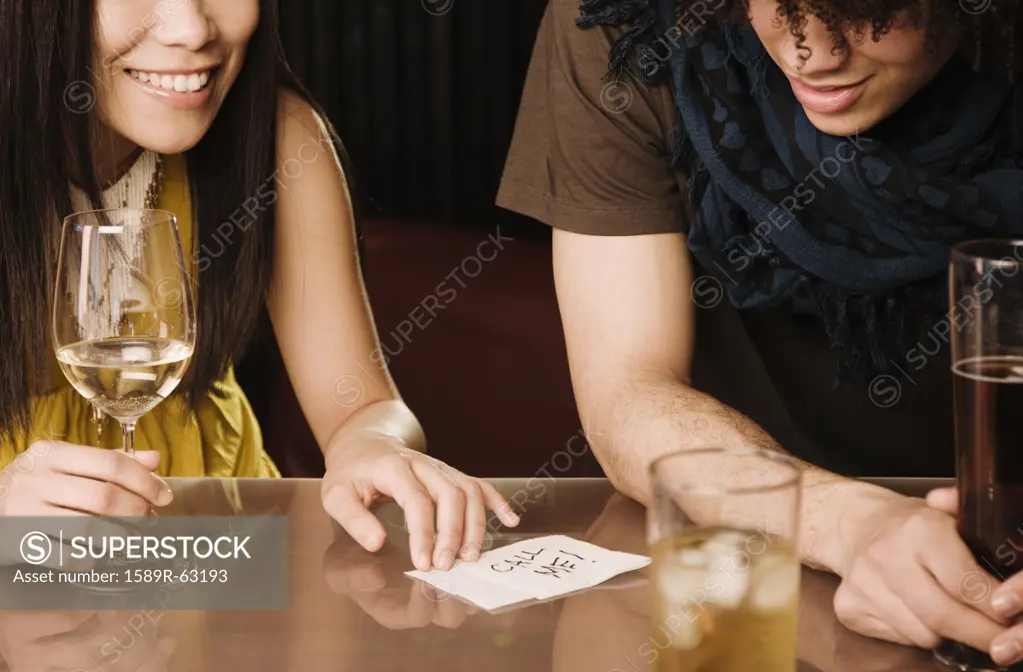Asian woman giving mixed race man her phone number in nightclub