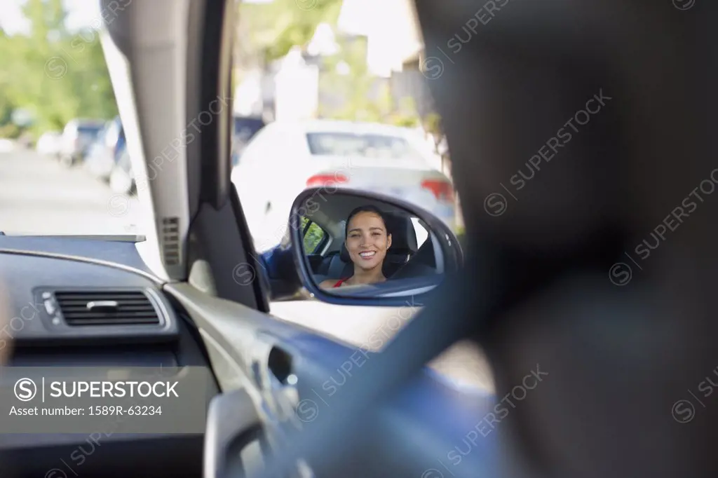 Image of Hispanic woman in cars side mirror