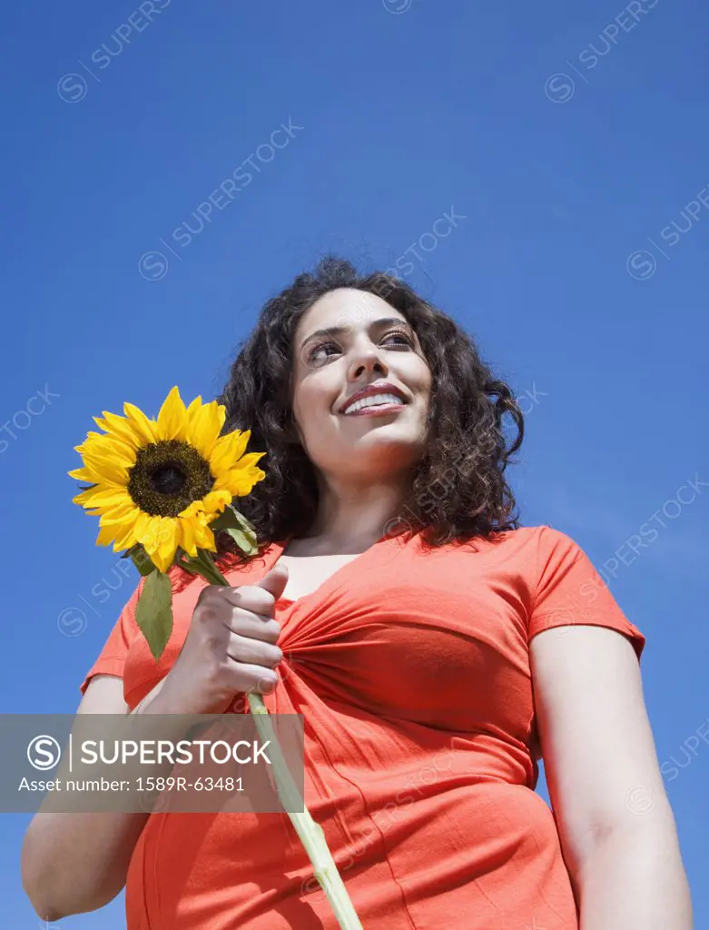 Mixed race woman holding sunflower outdoors