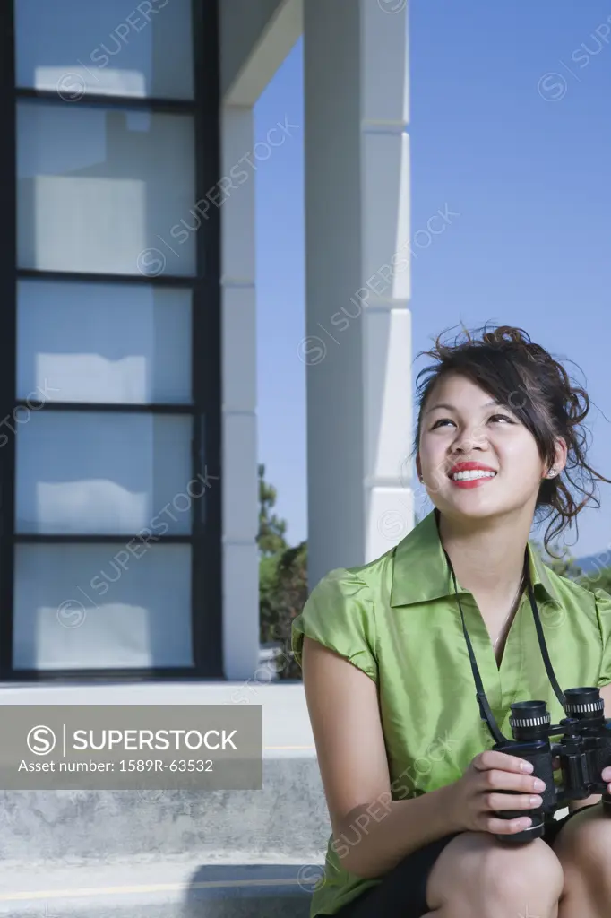 Asian businesswoman sitting outdoors with binoculars